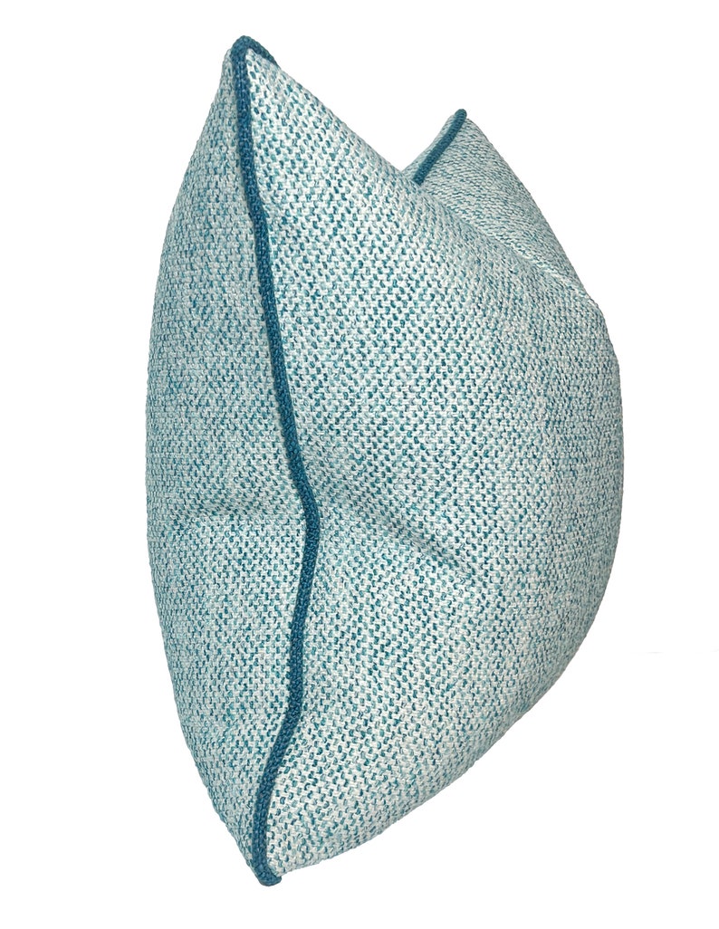 May include: A blue and white patterned throw pillow with a blue border. The pillow is made of a soft, textured fabric.