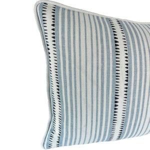 May include: A blue and white striped throw pillow with black trim. The pillow has a geometric pattern on the trim.