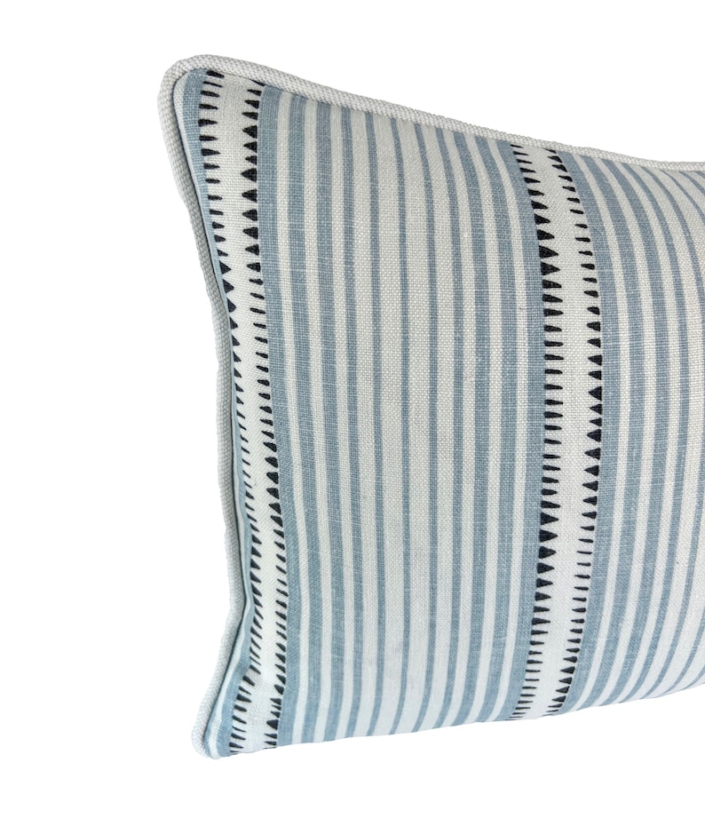 May include: A blue and white striped throw pillow with black trim. The pillow has a geometric pattern on the trim.