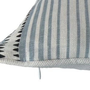 May include: A blue and white striped pillow with a black and white geometric pattern on one side. The pillow has a zipper closure.