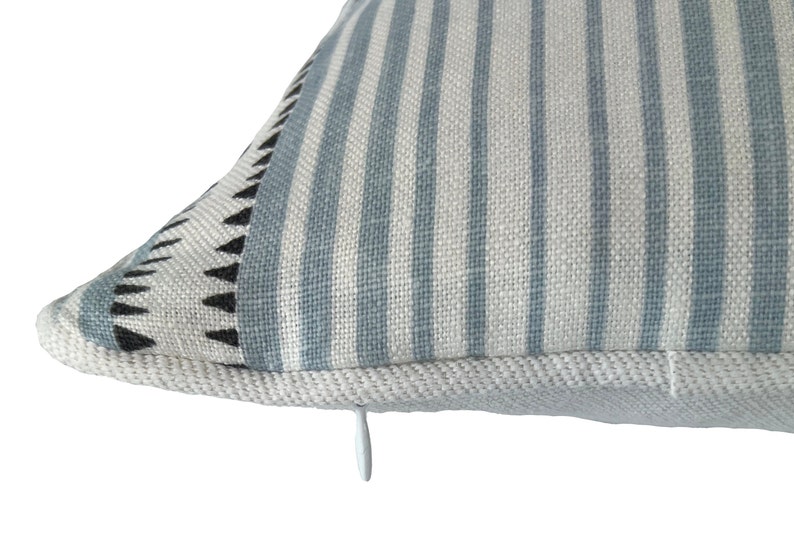 May include: A blue and white striped pillow with a black and white geometric pattern on one side. The pillow has a zipper closure.