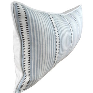 May include: A long, rectangular lumbar pillow with a white background and blue and black stripes. The pillow has a white piping around the edges.