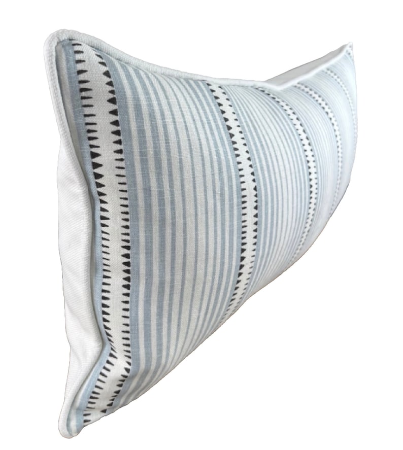 May include: A long, rectangular lumbar pillow with a white background and blue and black stripes. The pillow has a white piping around the edges.