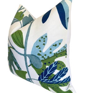 May include: A decorative cushion with a white backdrop and a botanical design. The pattern showcases large leaves in shades of green and blue. The cushion is square in shape.