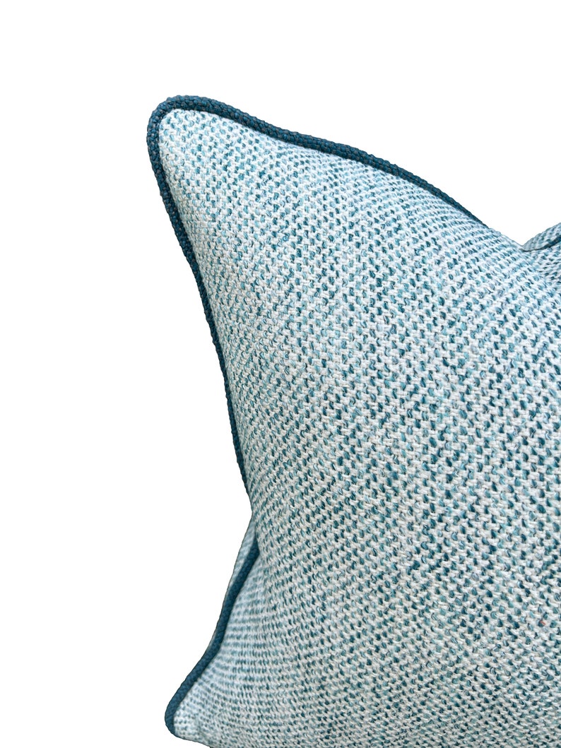 May include: A blue and white patterned throw pillow with a dark blue trim. The pillow is made of a woven fabric and has a soft, comfortable feel.