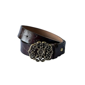 May include: A brown leather belt with an ornate gold-toned buckle. The belt is decorated with a floral pattern.