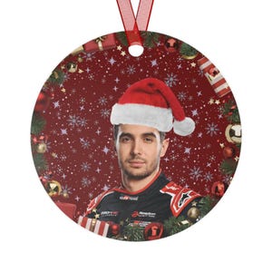 Op de afbeelding: Ronde kerstversiering met een man met een kerstmuts. De versiering heeft een rode achtergrond met sneeuwvlokken en kerstversieringen. Een rood lint is bevestigd om op te hangen.