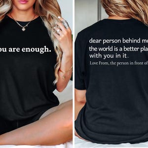 May include: Black t-shirt with the text "you are enough." on the front and the text "dear person behind me, the world is a better place with you in it.. Love From, the person in front of you." on the back.