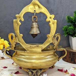 Pu&ograve; includere: Un bruciatore di incenso in metallo dorato con una campana appesa in cima. Il bruciatore ha una ciotola rotonda e una cornice decorativa con dettagli intricati. La campana &egrave; anch'essa dorata e ha una forma arrotondata.