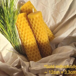 May include: Three yellow honeycomb-patterned candles with a white wick, resting on a white cloth. Green pine needles are to the left. The candles are approximately 4.7 inches tall and 1.3 inches wide.