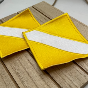 May include: Two yellow fabric patches with a white diagonal stripe. The patches are sewn with a white thread.