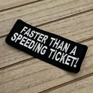 May include: Black and white embroidered patch with the text "Faster than a speeding ticket!"