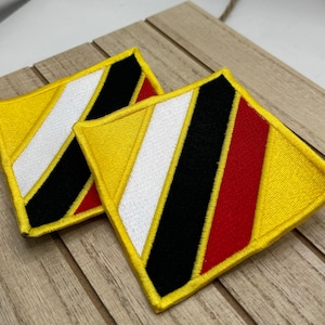 May include: Two yellow diamond-shaped patches with black, white, and red stripes. The patches are sewn together and have a yellow border.