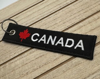 May include: Black fabric keychain with a red maple leaf and the word "CANADA" in white lettering.