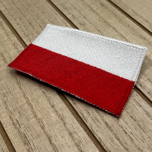 May include: A red and white fabric patch with a stitched border, resembling the flag of Poland.