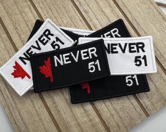 May include: A set of four embroidered patches with the text "NEVER 51" and a red maple leaf. Two patches are white with black text and two patches are black with white text.