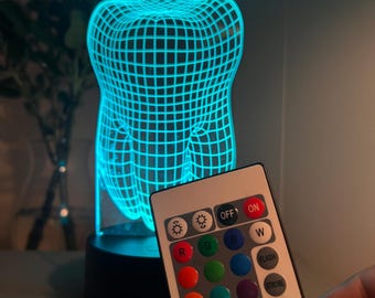 Luz nocturna 3D con forma de diente: cambia de color y incluye control remoto.