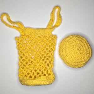 May include: A yellow crocheted tote bag with a matching yellow crocheted round lid. The bag has a honeycomb pattern and two straps.