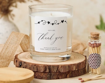 May include: A vanilla-scented candle in a clear glass jar with a label that reads "Just a Big Thank You." The candle sits on a wooden slice with a small glass bottle of matches. The candle has a 25-hour burn time.