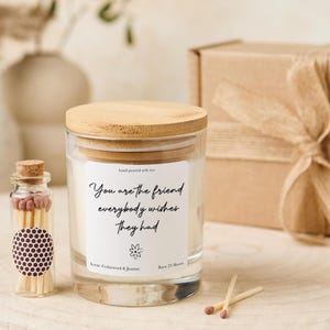 Può includere: Un barattolo di candela in vetro trasparente con coperchio in legno e un'etichetta che recita "You are the friend everybody wishes they had." Sono presenti anche una piccola bottiglia di fiammiferi e una confezione regalo.