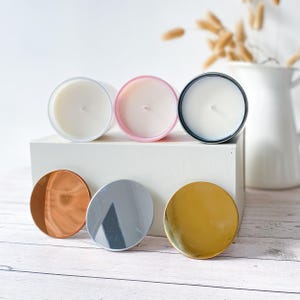 以下が含まれることがあります： 蓋付きの白いキャンドルジャー3つ、ピンク、黒、白。蓋は金、銀、銅です。