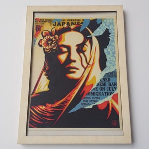 Puede incluir: Una impresión enmarcada de la cara de una mujer con una flor en el pelo. La impresión está en un estilo que recuerda a un cartel vintage. El texto en la impresión dice "ALL PERSONS OF JAPANESE...GNED JAPANESE BAN...IVE ON JULY IMMIGRATION...MITED ENTRY FOR SEVEN SPECIAL TWO".