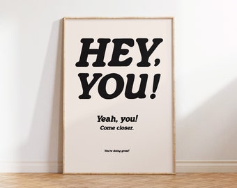 May include: A black and white poster with the text "HEY, YOU!" in a bold, retro font. The text "Yeah, you! Come closer. You're doing great!" is printed below in a smaller font.