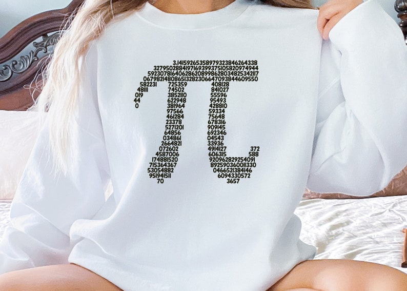 May include: White sweatshirt featuring a black graphic of the mathematical constant pi, displayed as a sequence of numbers arranged in the shape of the Greek letter pi.
