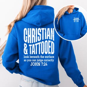 May include: A royal blue hoodie with white text on the back that reads "CHRISTIAN & TATTOOED" with the text "look beneath the surface so you can judge correctly JOHN 7:24". The front of the hoodie has the text "JOHN 17:24".