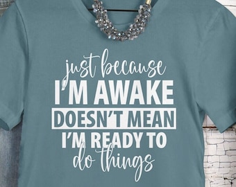 May include: A teal blue t-shirt with the text "just because I'm awake doesn't mean I'm ready to do things" in white.