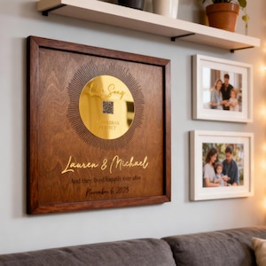 May include: A wooden framed plaque with a gold circular design and the text "Lauren & Michael" and "And they lived happily ever after November 6, 2025". The plaque is surrounded by family photos and plants.