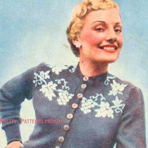 May include: A blue cardigan with white floral embroidery and button closures. The cardigan is worn by a woman with blonde hair and a smile.