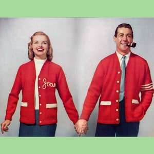 May include: A red cardigan with white trim and a white embroidered name "Joan" on the left side. The cardigan is buttoned up and has a white undershirt. The person is holding hands with another person wearing a red cardigan with white trim and a white undershirt.