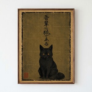 Könnte beinhalten: Ein gerahmter Kunstdruck mit einer schwarzen Katze mit bernsteinfarbenen Augen vor einem strukturierten, goldfarbenen Hintergrund. Vertikale japanische Kalligrafie ist über der Katze zentriert, und ein kleines rotes quadratisches Siegel befindet sich unten links.