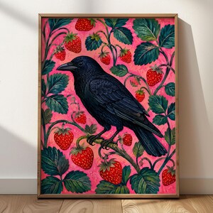 May include: A framed rectangular wall art print featuring a black crow perched on a strawberry plant vine. The background is a vibrant pink, filled with numerous red strawberries and dark green leaves surrounding the central bird figure.
