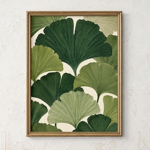 Könnte beinhalten: Ein gerahmter Kunstdruck mit einem sich wiederholenden Muster aus Ginkgo-biloba-Blättern in verschiedenen Schattierungen von dunklem Waldgrün und hellem Salbeigrün auf cremefarbenem Hintergrund, eingefasst in einen dünnen, strukturierten Goldrahmen.
