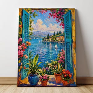Könnte beinhalten: Ein rechteckiger Leinwanddruck, der ein offenes Fenster mit hellblauen Fensterläden zeigt, das den Blick auf eine mediterrane Küstenlandschaft freigibt. Zu sehen sind ein tiefblaues Meer mit Segelbooten, Berge und rosa Blumen.