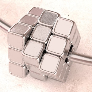 May include: A silver metal cube with a textured surface. The cube is made up of smaller squares that are arranged in a grid pattern. The cube is attached to a silver metal rod.