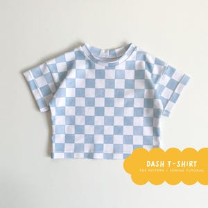 Könnte beinhalten: Ein hellblaues kariertes T-Shirt mit kurzen Ärmeln. Das T-Shirt ist ein Schnittmuster mit einem PDF-Download und einer Nähanleitung. "Dash T-Shirt" steht in gelber Schrift auf einer gelben Wolke.