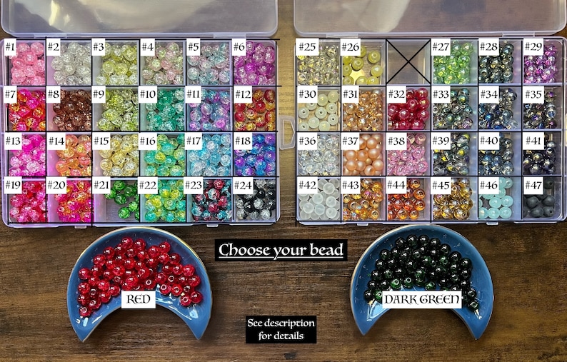 May include: A clear plastic storage box filled with various colored beads. The beads are numbered 1 through 47. There are two smaller dishes with red and dark green beads, labeled "RED" and "DARK GREEN". The text "Choose your bead" is printed below the storage box.