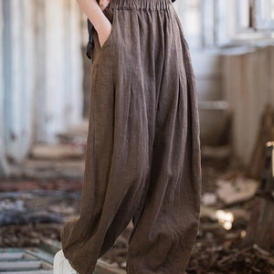 May include: Brown linen pants with a wide leg and elastic waistband. The pants have a relaxed fit and are made of a lightweight fabric.