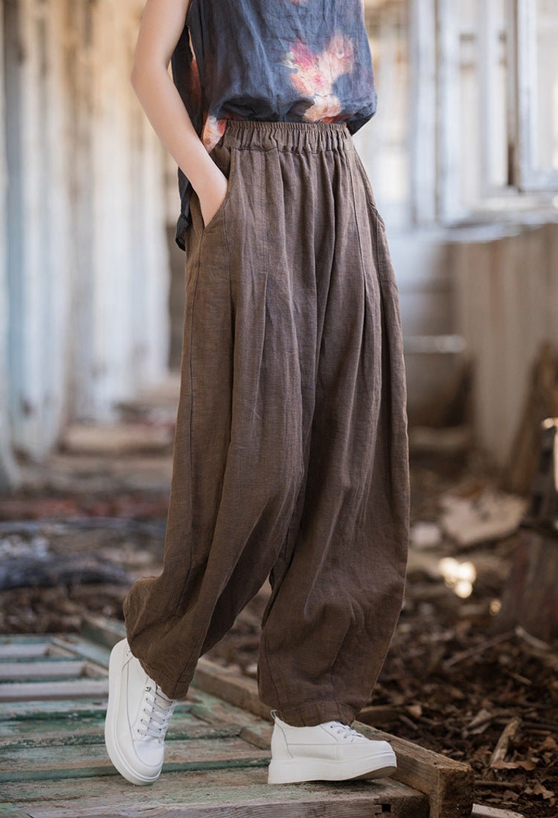 May include: Brown linen pants with a wide leg and elastic waistband. The pants have a relaxed fit and are made of a lightweight fabric.