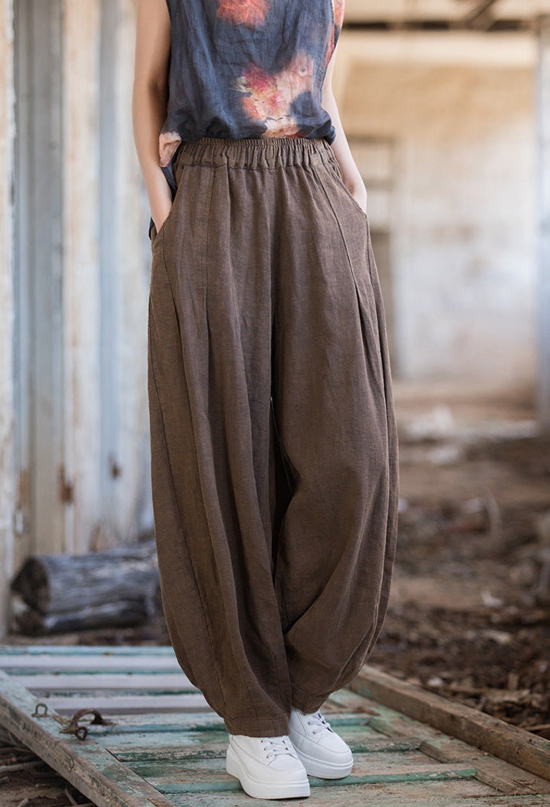 May include: Brown linen pants with a wide leg and elastic waistband. The pants have pockets on the sides and are made of a soft, comfortable fabric.