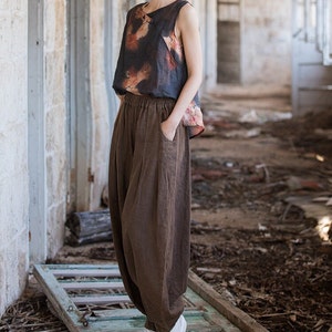 May include: A brown linen wide-leg pant with a drawstring waist and pockets. The pants are loose-fitting and flowy.