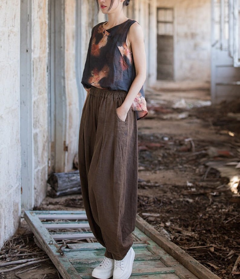 May include: A brown linen wide-leg pant with a drawstring waist and pockets. The pants are loose-fitting and flowy.