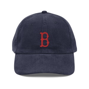 May include: A navy blue corduroy baseball cap with a red embroidered "B" on the front.