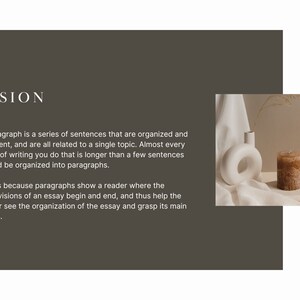 May include: A white ceramic vase with a circular opening sits on a white fabric surface next to a brown candle. The candle is on a white rectangular surface. The background is a light brown wall.