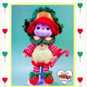 May include: A vintage crochet doll named Peppermint Stick, with a red yarn wig and a green and yellow hat. The doll wears a red and white outfit, red shoes, and holds a candy cane. The text "Brought to you directly from Lollipop Lane" is at the bottom.