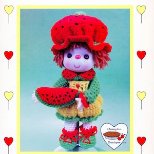 Puede incluir: Muñeca de ganchillo vestida como una rodaja de sandía, con un sombrero rojo con semillas negras, un vestido verde y amarillo y zapatos rojos. La muñeca sostiene una rodaja de sandía. El texto "Watermelon Slice" y "Brought to you directly from Lollipop Lane" son visibles.