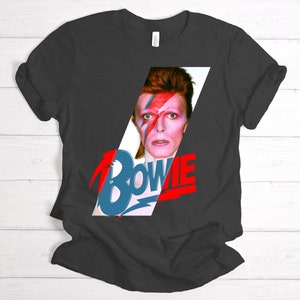 May include: A black t-shirt with a graphic of David Bowie's face and the word "BOWIE" in red and blue letters.